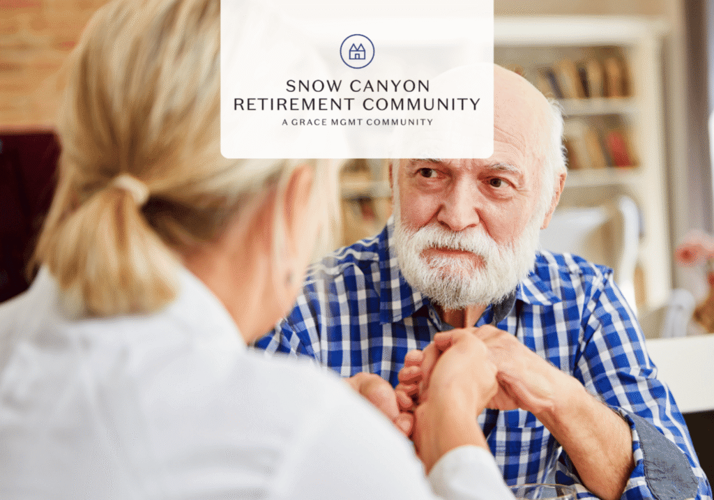 Elderly man with white beard and a caregiver share a moment, hands clasped, in a cozy retirement home setting in a retirement community.